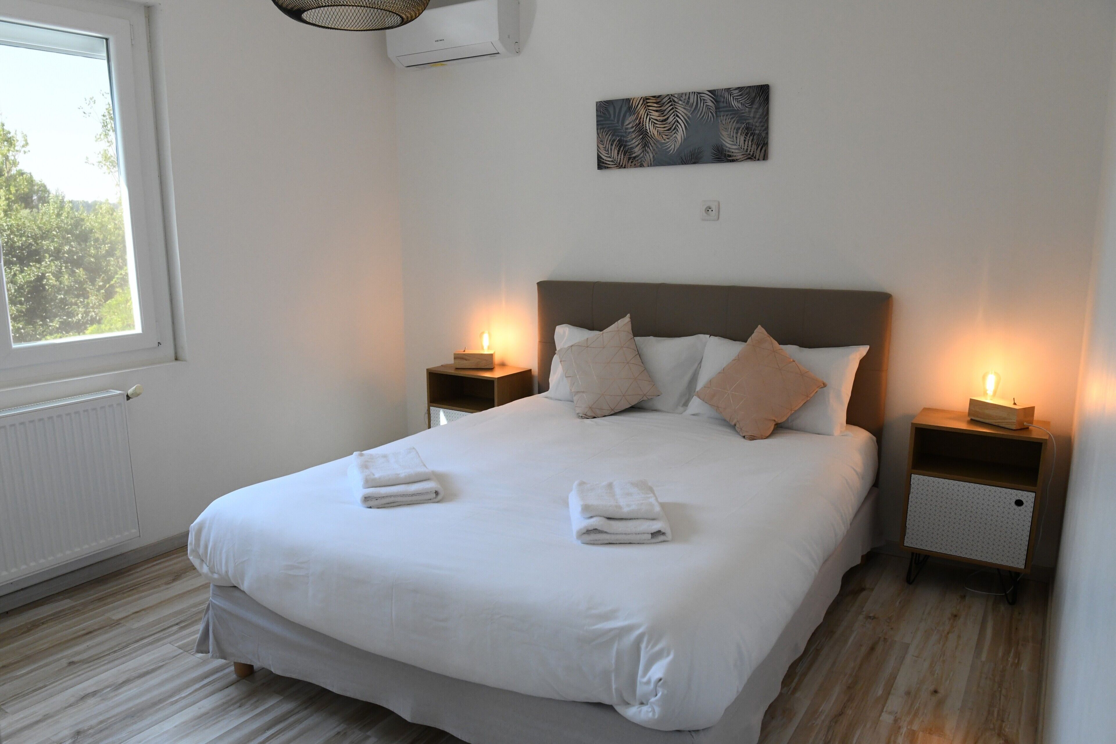 Un lit bien fait, avec des oreillers et une table de chevet sur laquelle se trouve une lampe.