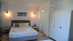Een slaapkamer met een groot bed, twee nachtkastjes, een kledingkast en een schilderij aan de muur.