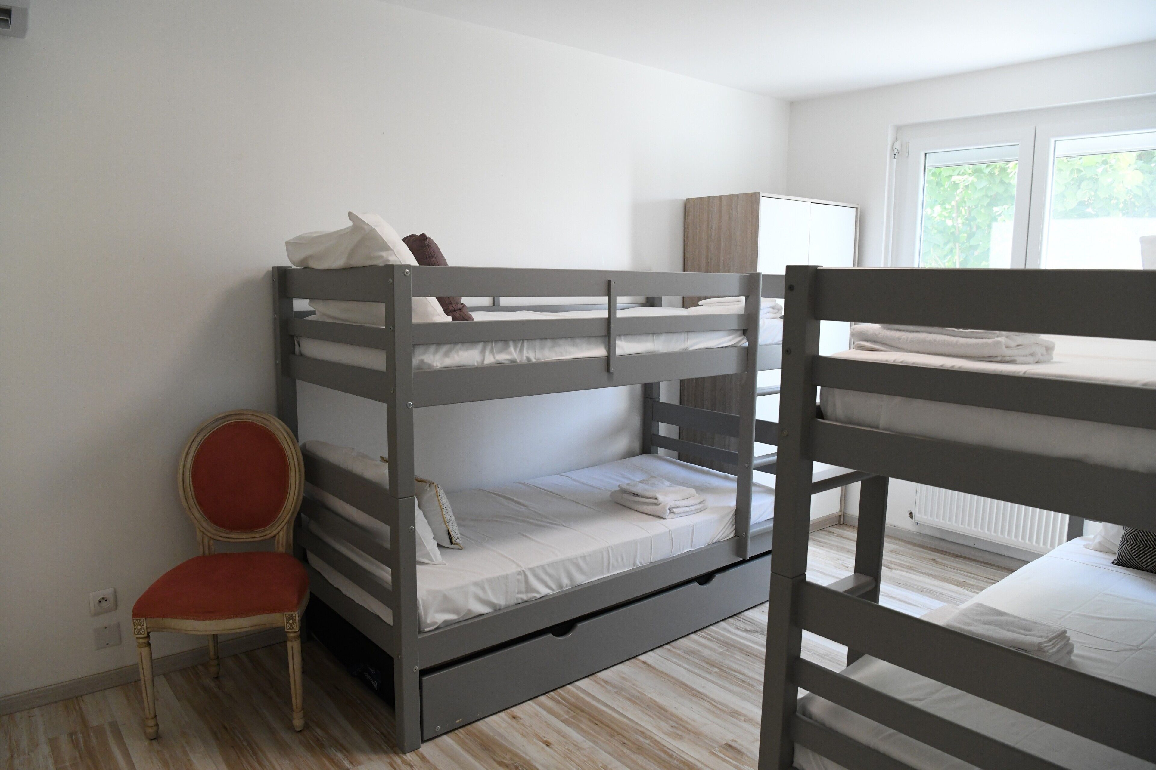 Une chambre avec un lit superposé, une chaise, un radiateur et une fenêtre.