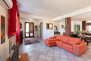 A living room with a sectional sofa, a TV, a fireplace, and a dining area. - Villa "Water Front Scopello" with Sea View, Private Beach Access, Garden, and Wi-Fi (Scopello)