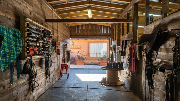 L’intérieur d’une grange en bois, avec un plancher en béton, des murs en bois et un toit en métal.