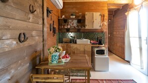 Un intérieur en bois comprenant un coin cuisine, avec une table et des chaises, un four à micro-ondes et un évier.