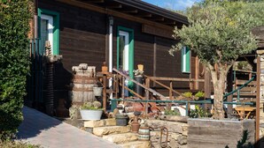 Un bâtiment rustique en bois, doté d’un escalier en pierre, d’une clôture en bois et d’un arbre.