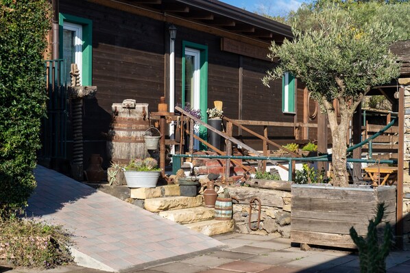 A rustic wooden building with a stone staircase, a wooden fence, and a tree.