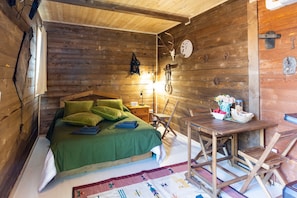 Una habitación de cabaña de madera con una cama, una mesa y una silla.