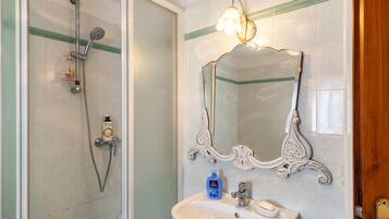 Une salle de bain équipée d’une douche, d’un lavabo, d’un miroir et d’un luminaire.