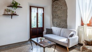 Uma sala de estar com um sofá, uma mesa de centro, uma parede de pedra e uma porta decorada com corações.