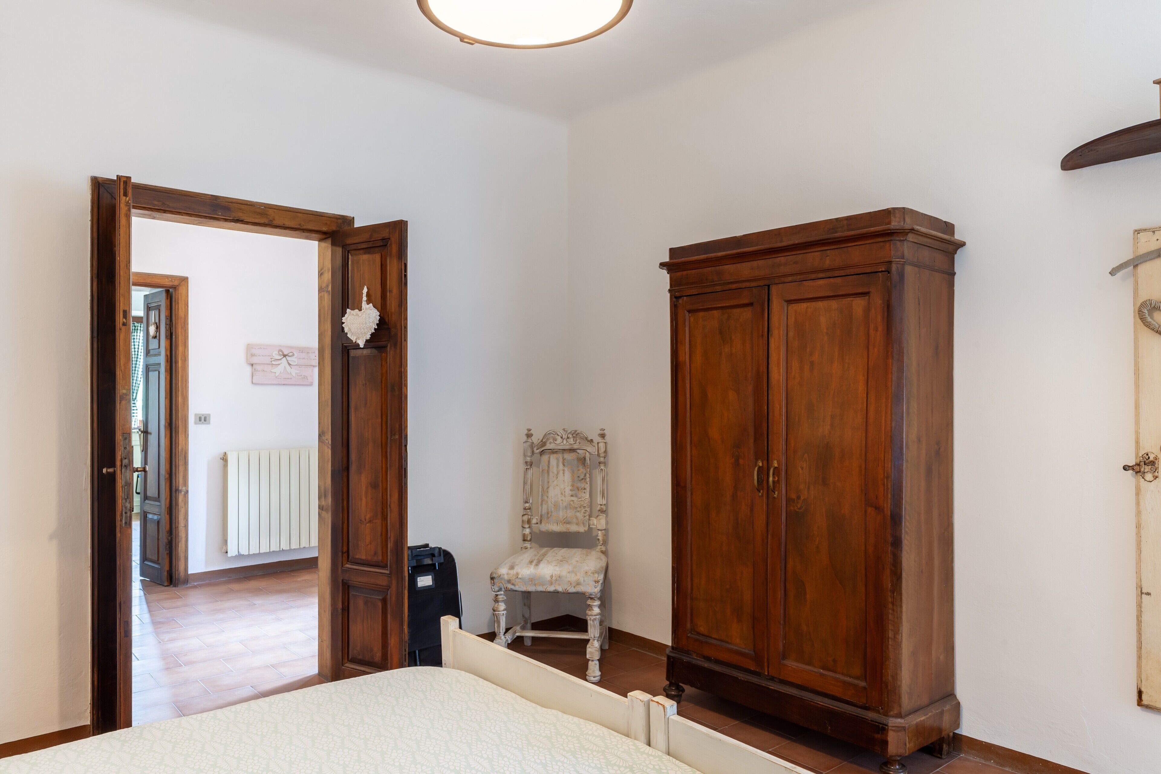 Une chambre avec une armoire en bois, une chaise, un radiateur et un lit.