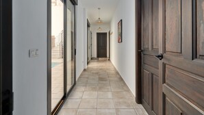A hallway with a tiled floor, sliding glass doors, and wooden doors. - Holiday Home "El Cine" with Mountain View, Pool & Wi-Fi (Canillas de Albaida)