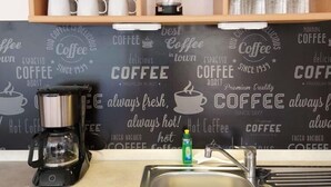 L'intérieur d'un café, avec une machine à café, des tasses et un tableau noir sur lequel sont écrites des expressions liées au café.