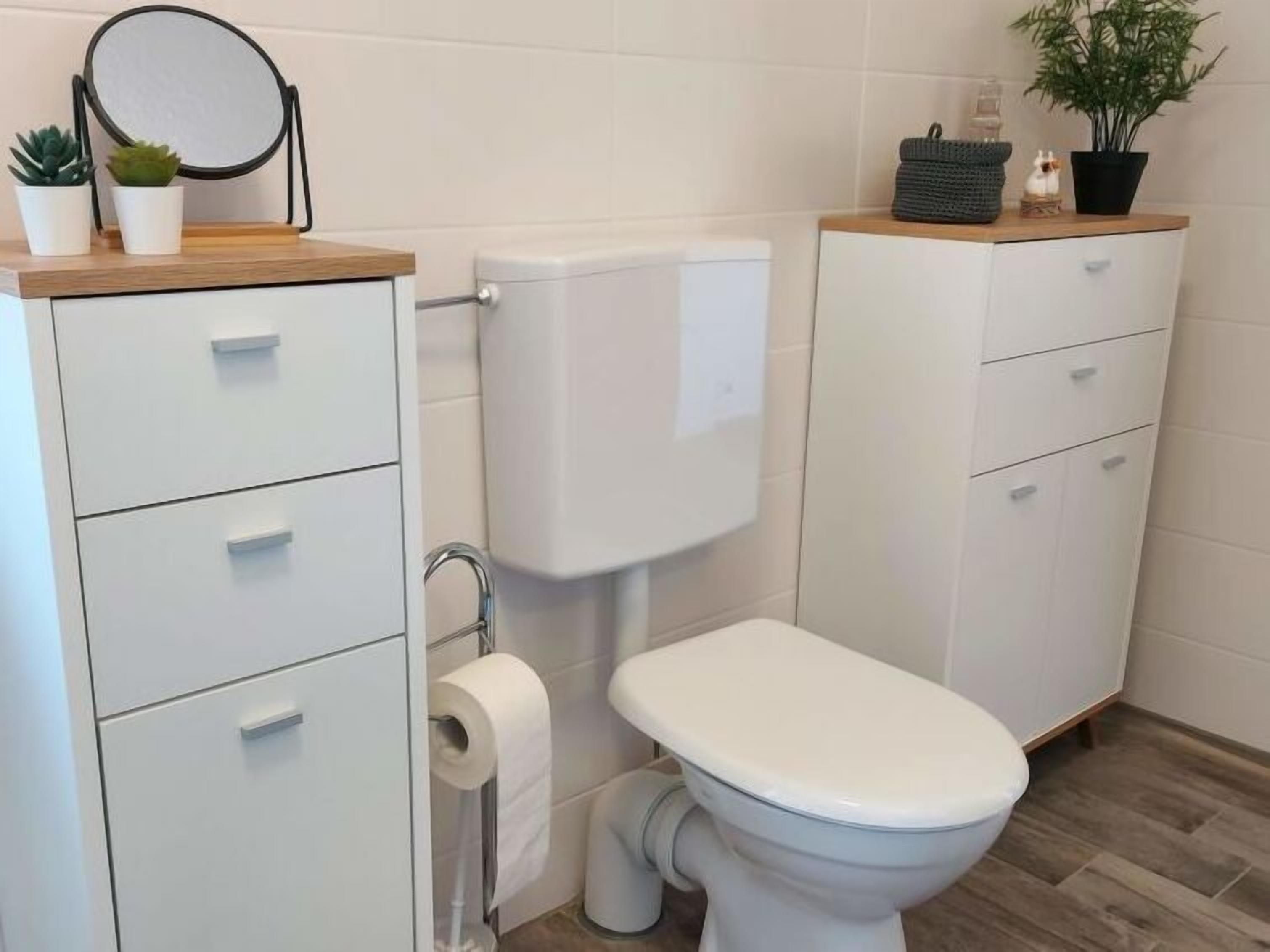 A modern bathroom with a toilet, a sink, and a cabinet.