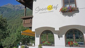 A building with a sign reading "Sonnenhof Apartments - Zimmer" and a balcony with wooden railings.
