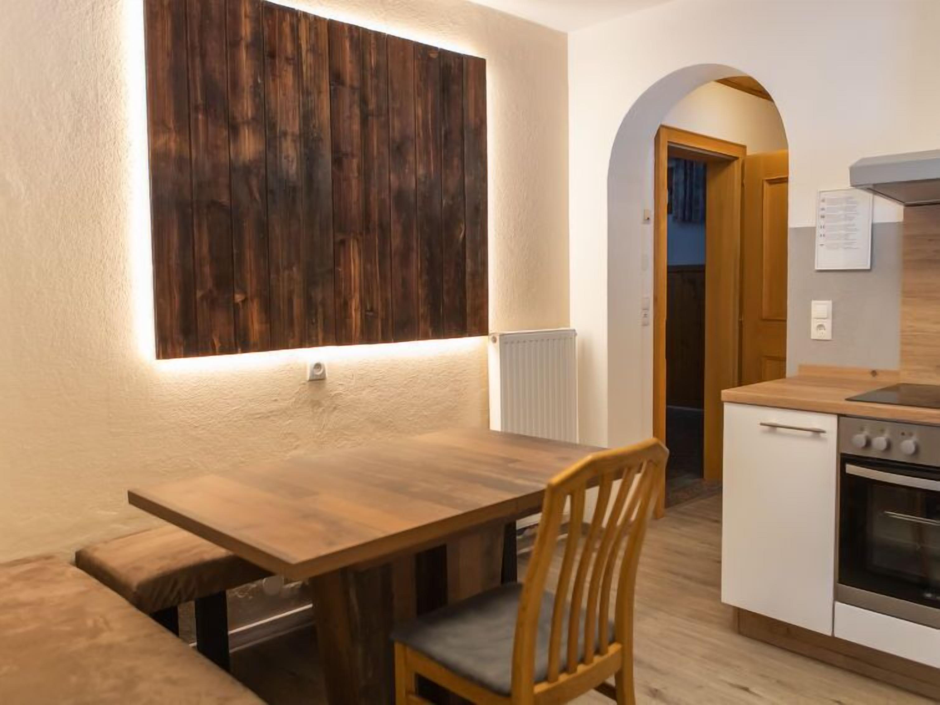 Una cocina compacta con una mesa de madera y un banco, un horno blanco y una estufa empotrada.