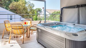 Ein Balkon mit Korbstühlen, einem Whirlpool und einem Glastisch mit einem Getränk.