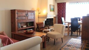 A cozy living room with a fireplace, wooden cabinet, and comfortable seating. - Les Girolles B15 by Interhome (Villars)