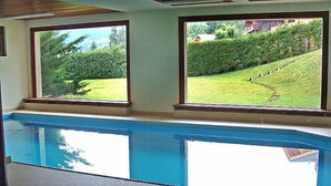 A swimming pool with a view of a well-maintained garden and a house in the background. - Les Girolles B15 by Interhome (Villars)