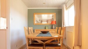 Een eetgedeelte met een houten tafel en stoelen, een spiegel aan de muur en een radiator.