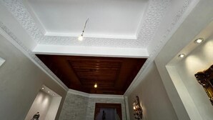 Una stanza con soffitto alto decorato da complesse lavorazioni bianche, travi in legno e illuminazione a incasso.