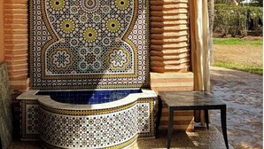Elemento architettonico tradizionale marocchino con decorazioni in piastrelle elaborate e un’area salotto.
