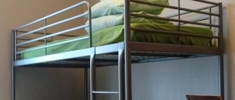 A bunk bed with a desk and chair, a radiator, and a red carpet.