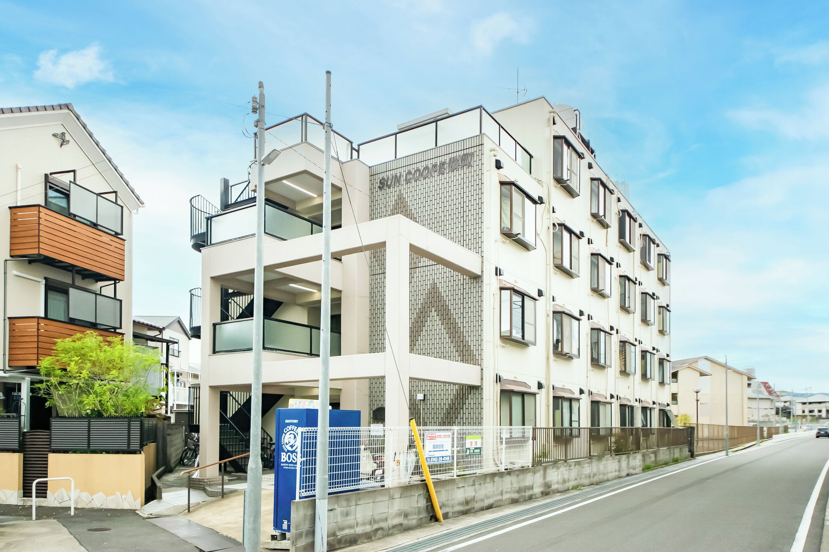 A modern multi-story building with balconies, a staircase, and a sign for a coffee shop.