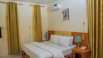 A hotel room with a bed, a nightstand with a lamp, and curtains.