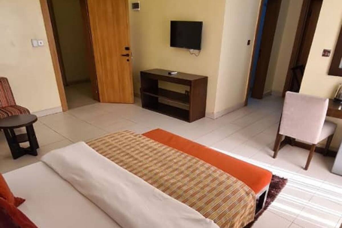 A hotel room with a bed, a TV, a desk, and a chair.