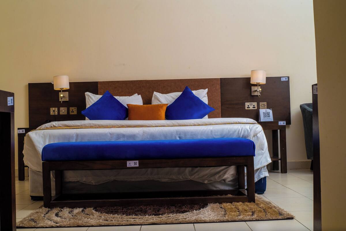 A neatly made bed with blue and white bedding, two bedside lamps, and a brown headboard.
