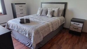 A neatly arranged bedroom with a bed, bedside tables, a wardrobe, and a ceiling fan. - Lovely 2 bedroom condo with nice amenities and on the bus line (Rochester)