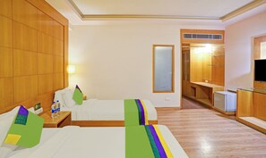 A hotel room with two beds, a desk, a mirror, and a television. - Treebo Royal Cm - City Center (Jaipur)