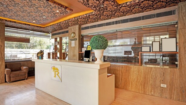 A reception desk with a clock, a potted plant, and a sign indicating a check-in area. - Treebo Royal Cm - City Center (Jaipur)