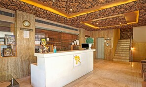 A hotel reception area with a marble reception desk, a clock, and a sign indicating no outside food entry. - Treebo Royal Cm - City Center (Jaipur)