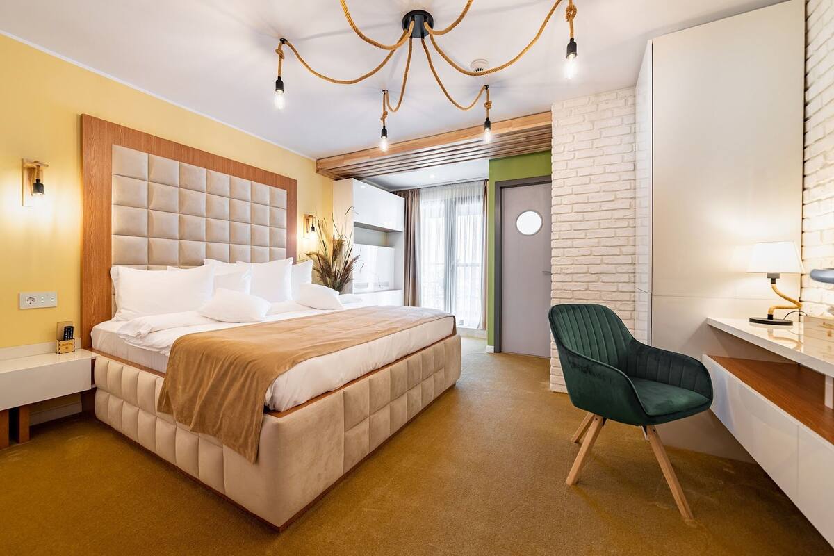 A modern hotel room with a large bed, a desk, and a chair.
