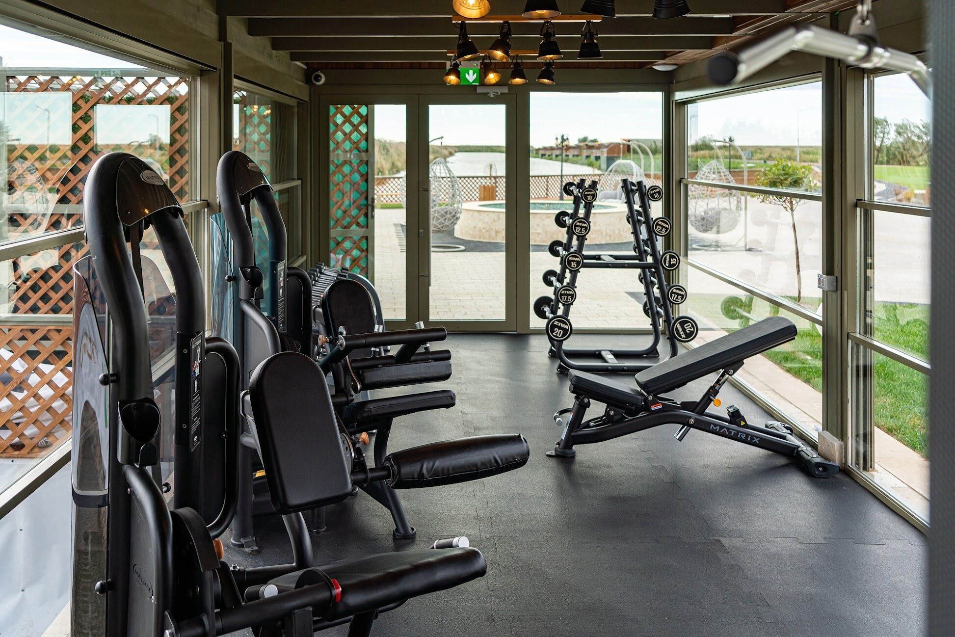 Ein Fitnessraum mit Trainingsgeräten, einer Bank und einem Squat-Gestell.