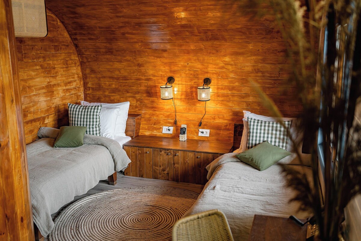A cozy cabin room with two beds, a small table, and two wall-mounted lamps.