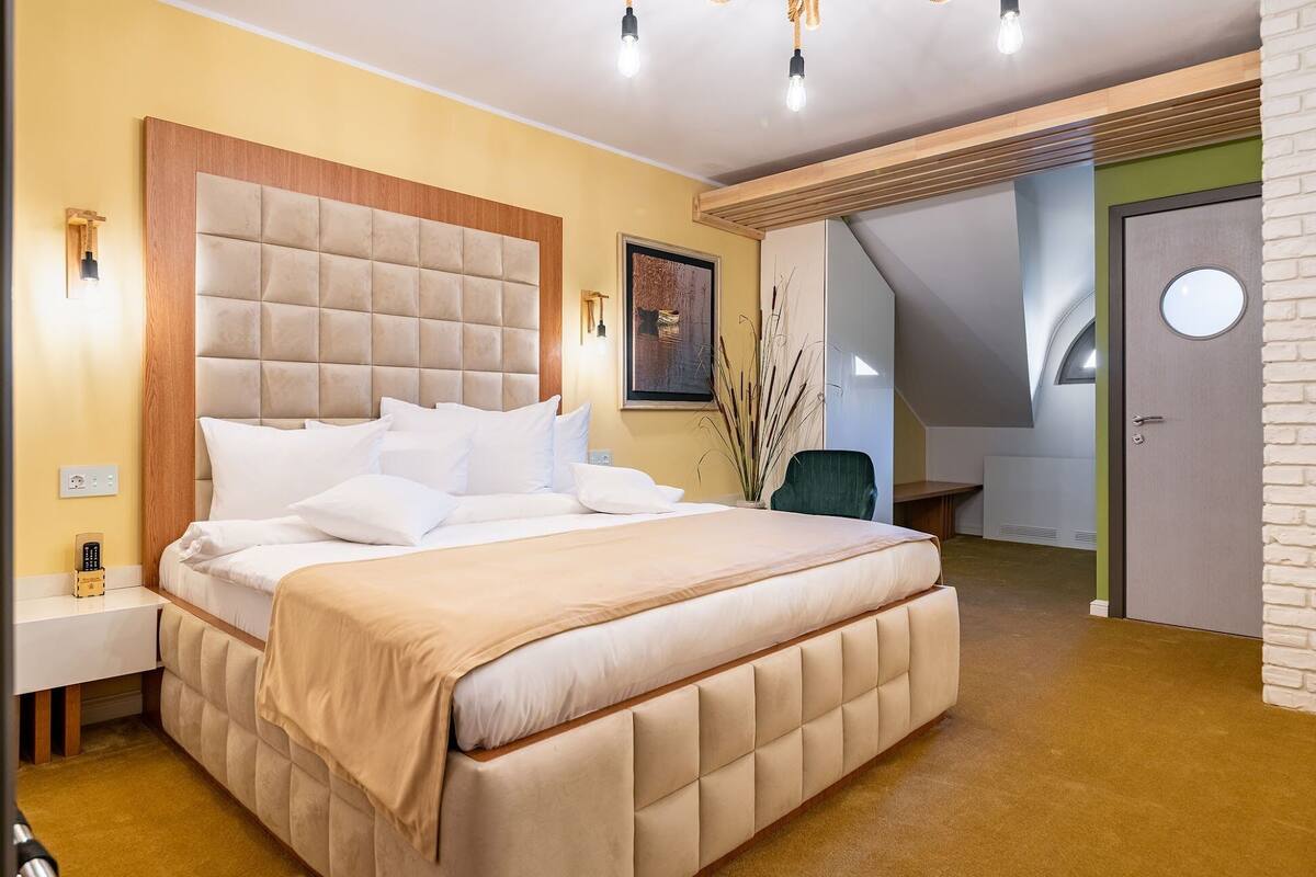 A bedroom with a large bed, bedside tables, a desk, and a chair.