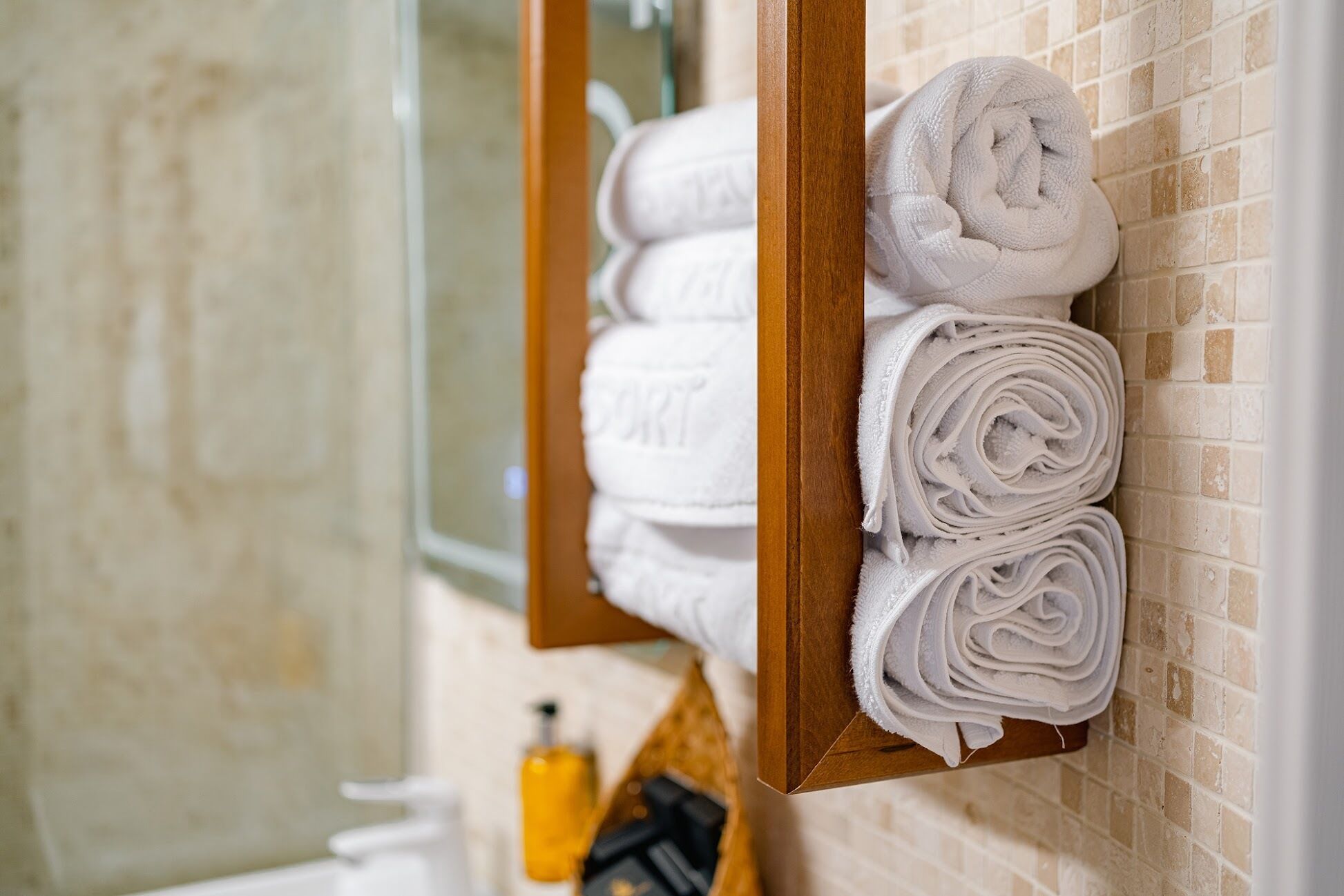 A bathroom with a wooden towel rack holding neatly folded white towels.