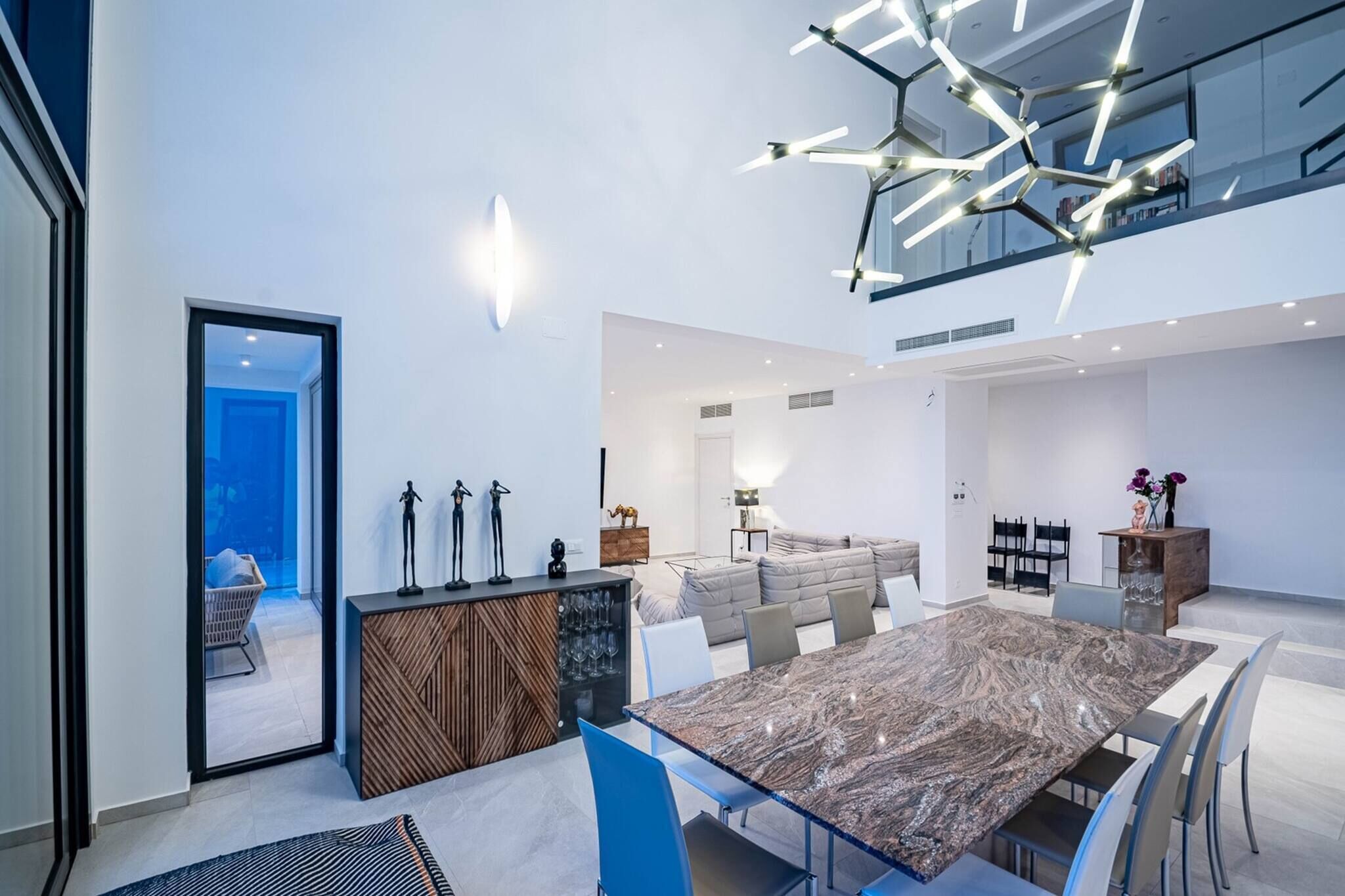 A modern interior with a dining area, a sofa, a coffee table, and a unique ceiling light fixture.