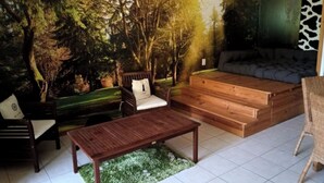 A room with a mural of a forest, a sofa, a wooden bench, a chair, and a small table.