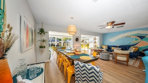 A modern dining area with a long table, yellow chairs, and a ceiling fan. - Tangerine Surfer (Clearwater)