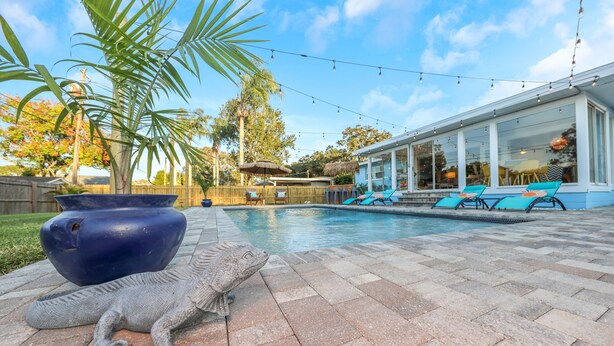 A pool area with lounge chairs and a large decorative fish sculpture. - Tangerine Surfer (Clearwater)