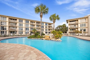 A hotel with a swimming pool, palm trees, and a clear blue sky. - Relax In Style at This Ground-Floor Corner Unit w/Patio Gulf Views & Pickleball (Seacrest Beach)
