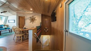 Un interior de madera con comedor, una escalera y un amplio ventanal.