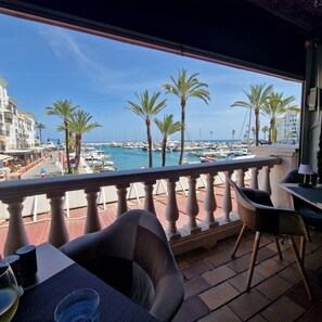 Ein Balkon mit Blick auf einen Yachthafen, Palmen und Gebäude.