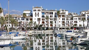A marina with white buildings, palm trees, and boats. - Stylish 2 bed 2 bath property on Duquesa Fairways , 2 terraces,  2 pools (Manilva)