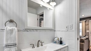 A bathroom with a white vanity, a large mirror, and a towel rack. - Homelike, peaceful and centrally- home located in the hamlet of Rocky  Point  NY (Rocky Point)