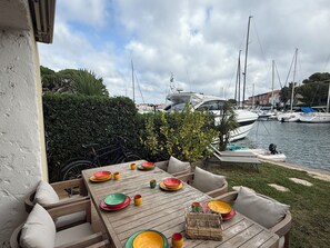 Un espace extérieur aménagé pour prendre les repas, avec vue sur un port de plaisance et des bateaux.