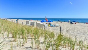 A beach with a fence, American flags, and beach umbrellas. - Ocean Block 2 BR 2 BA Unit - Short Walk to the Beach! (Ocean City)