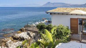 A coastal property with a terrace overlooking the sea, a white building with a tiled roof, and a garden area with tropical plants. - Rais house with private access to the sea (Solanto)