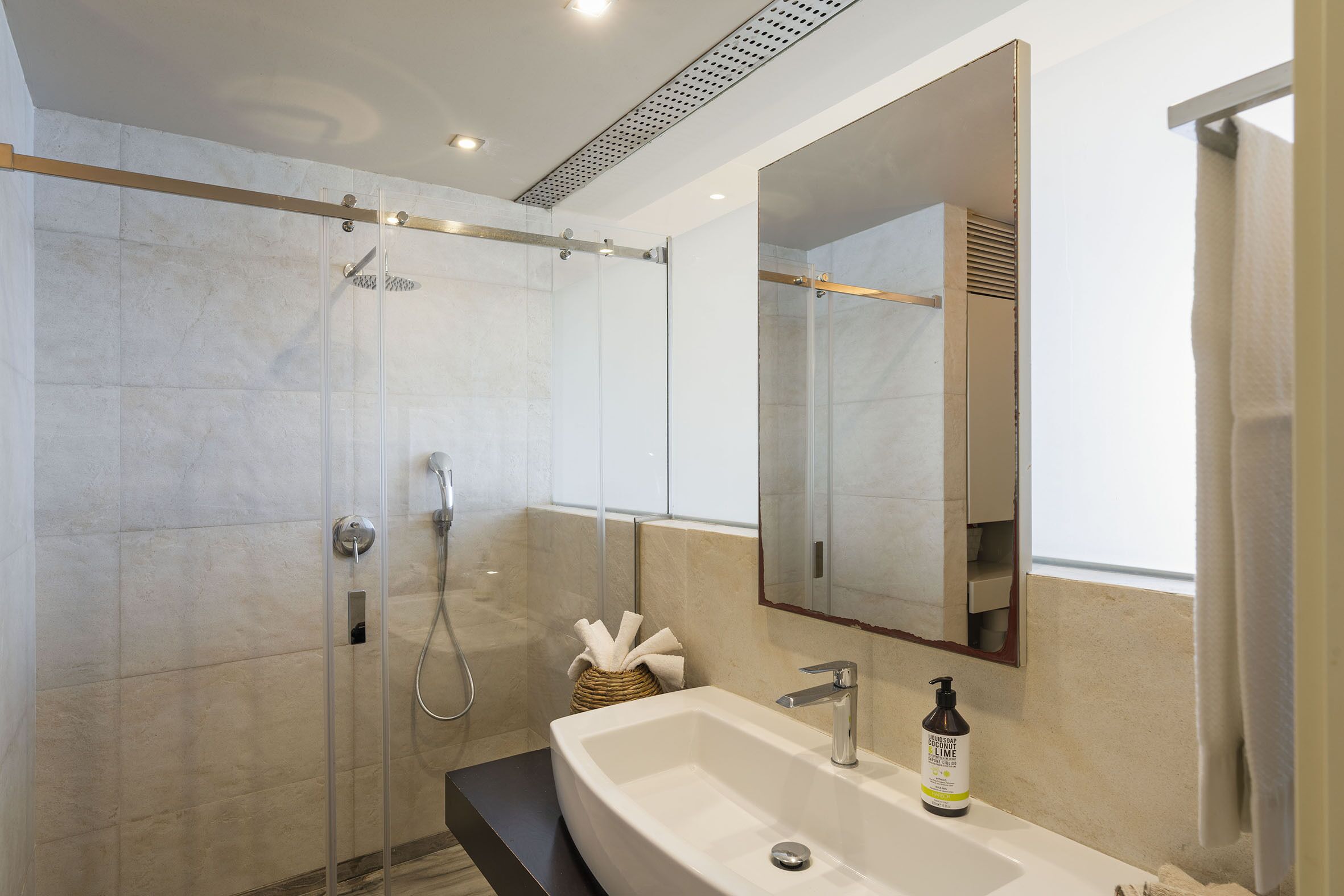 A modern bathroom with a glass-enclosed shower, a large sink, and a mirror.